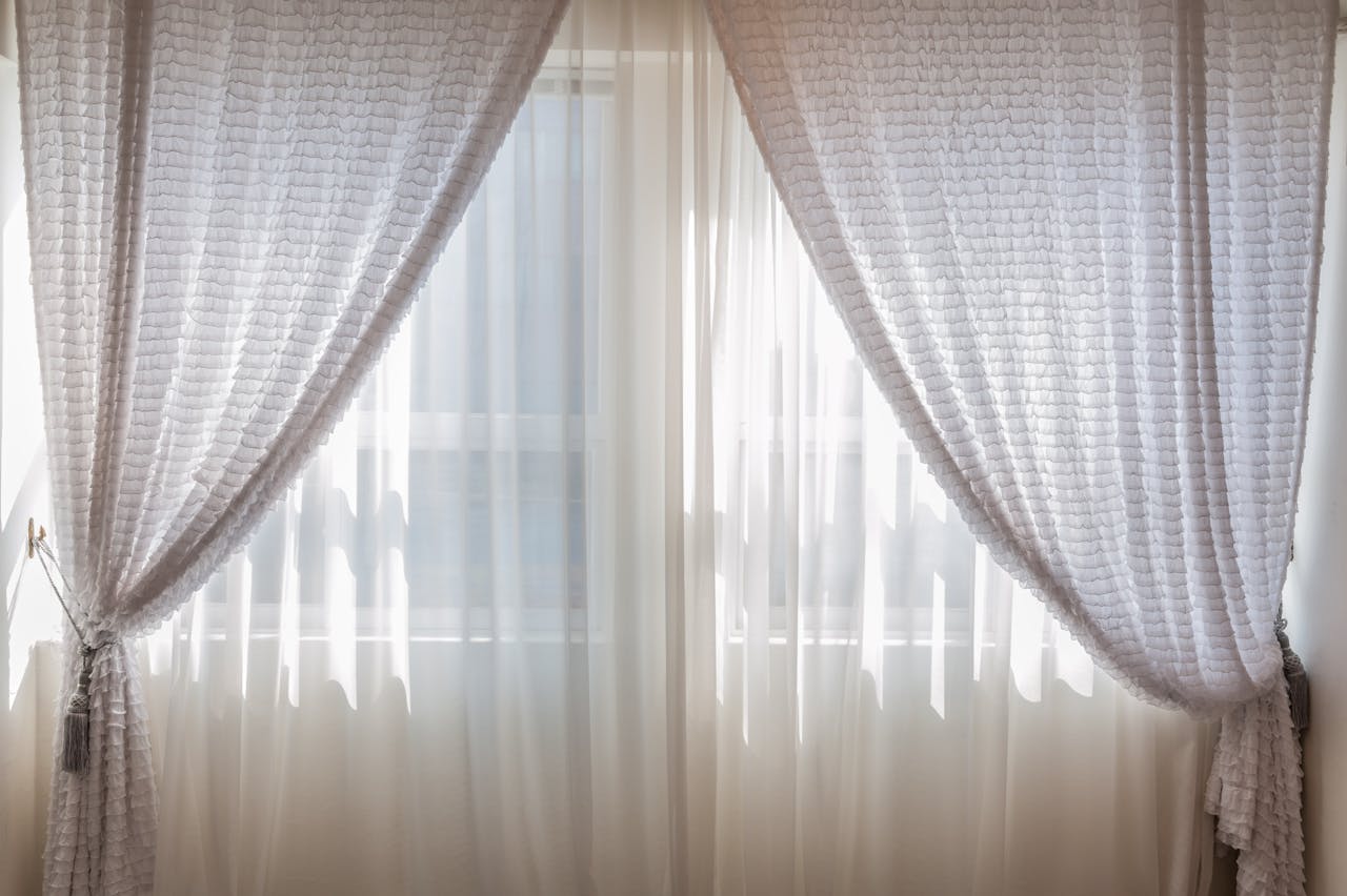 why-choose-us Sun shining through elegant white curtains in a cozy, modern interior setting.
