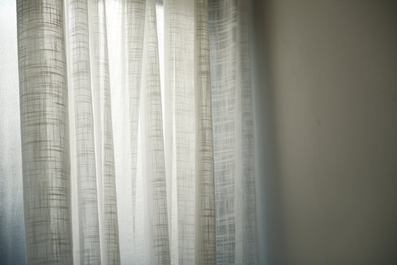 services-02 Sheer white curtains gently lit by daylight create subtle shadows on the wall.