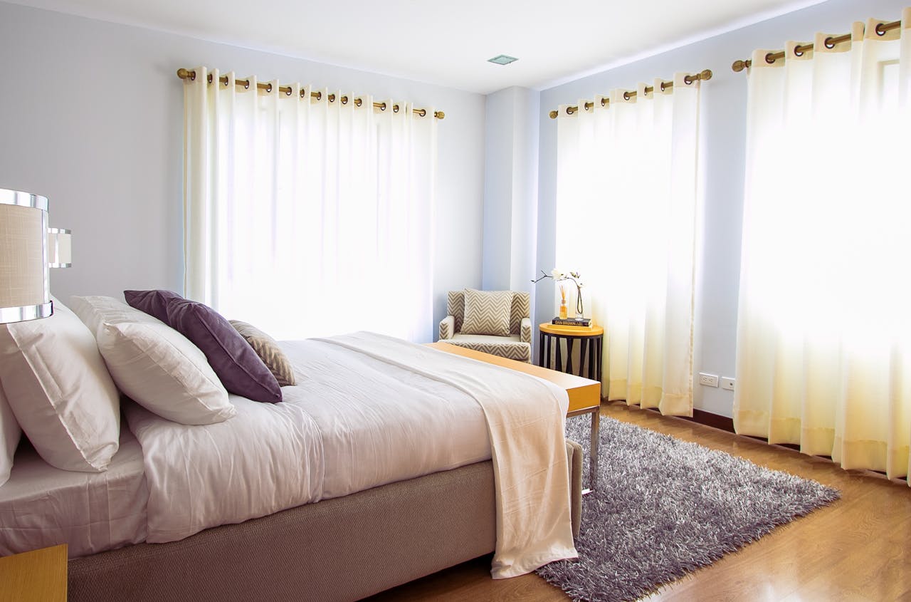 services-03 Bright modern bedroom with sunlight, cozy decor, and soft furnishings.